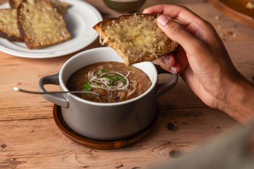 a person holding a piece of bread and a cup of soup at Campanile NATURE - Dreux in Dreux