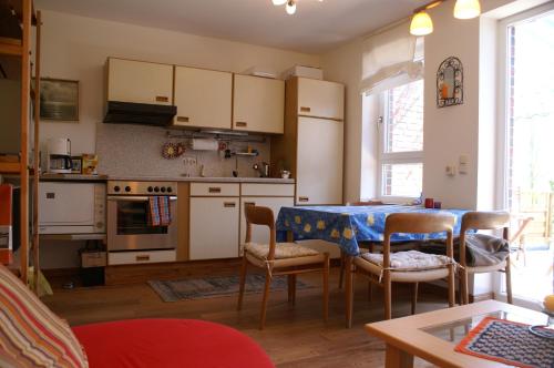 una cocina con mesa y sillas y una cocina con armarios blancos. en Emkendorf - An den Teichen, en Emkendorf