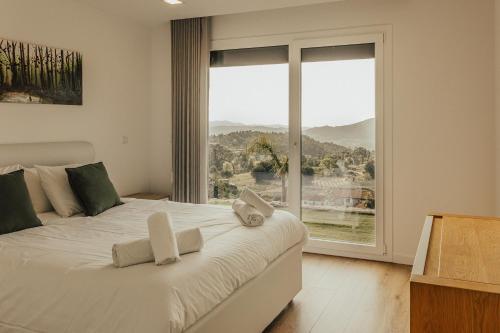 une chambre avec un grand lit blanc avec une grande fenêtre dans l'établissement Villa Cantinho da Cavadinha, à Arouca