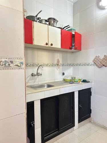 a small kitchen with a sink and red cabinets at STUDIO Wellness in Dakar