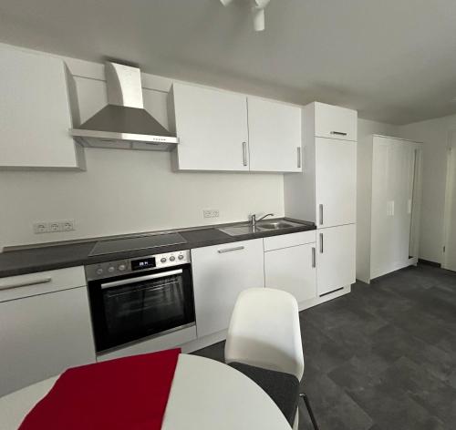 a kitchen with white cabinets and a sink and a table at Gemütliches Appartement in Bad Rothenfelde in Bad Rothenfelde
