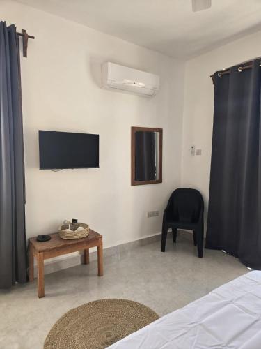 a bedroom with a tv and a chair and a table at Smile Boutique Beach hotel in Nungwi