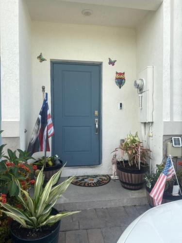 Una puerta azul en una casa con plantas y banderas. en Cozy rooms close to Florida Keys and more, en Florida City
