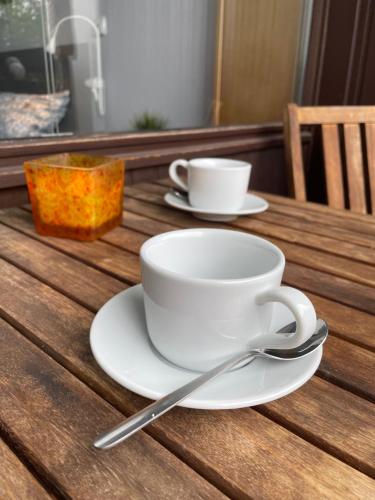 two white cups and saucers on a wooden table at Ferienwohnung in Freudenstadt-Kniebis II in Freudenstadt