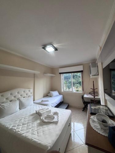 a bedroom with a large white bed and a desk at Flat Cavalinho Branco 119 in Águas de Lindoia