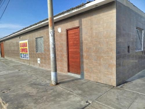 a brick building with a red door and a pole at Casa en Paracas para 7 personas in Paracas