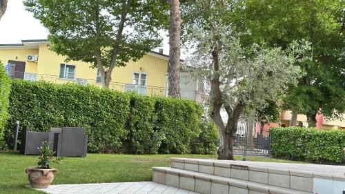 a plant in a pot in a park with a building at La Casa Bianca Rooms&Lounge in Cesenatico