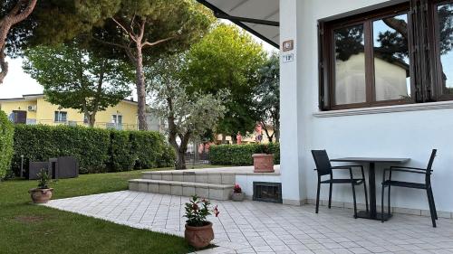 a patio with a table and chairs in a yard at La Casa Bianca Rooms&Lounge in Cesenatico