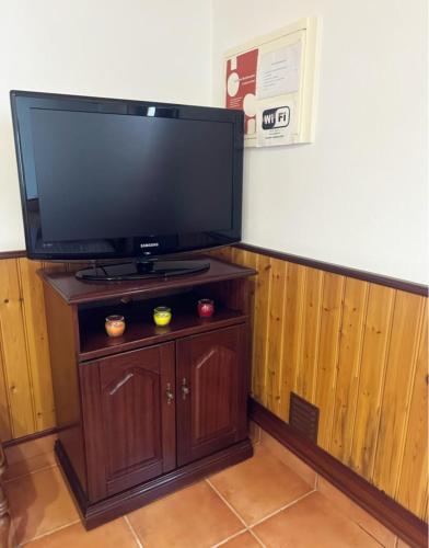 a flat screen tv sitting on top of a wooden stand at Casa Campo e Praia in Rogil