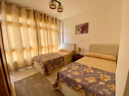 a bedroom with two beds and a window with curtains at Cairo Madinty 2 in Madinaty
