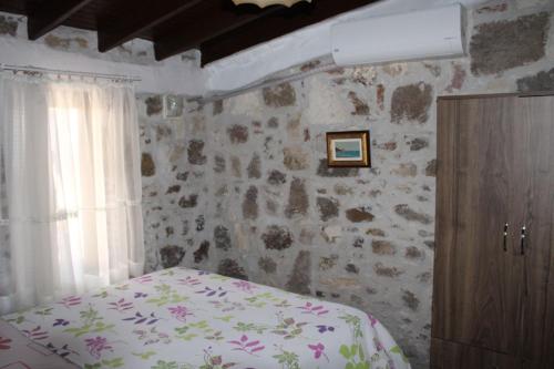 a bedroom with a bed and a stone wall at Denizkızı Sevilay Pansiyon in Ayvalık