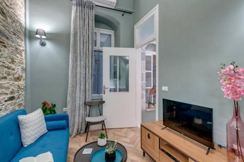 a living room with a blue couch and a tv at Nancy's Timeless Elegance in Ermoupoli