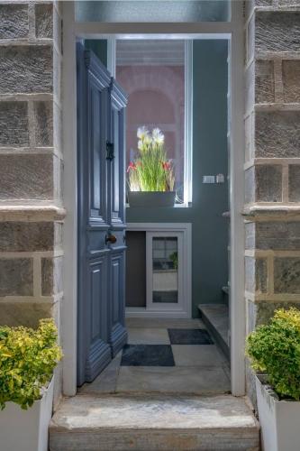 a blue door with a potted plant in a window at Nancy's Timeless Elegance in Ermoupoli