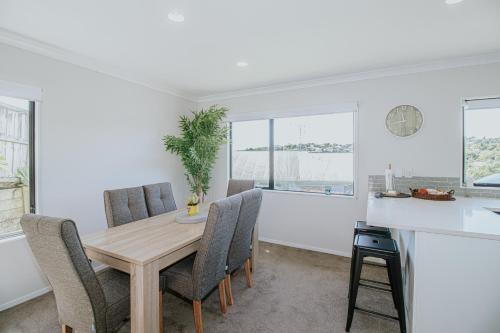 a kitchen and dining room with a wooden table and chairs at Views at Welcome Bay Heights in Tauranga