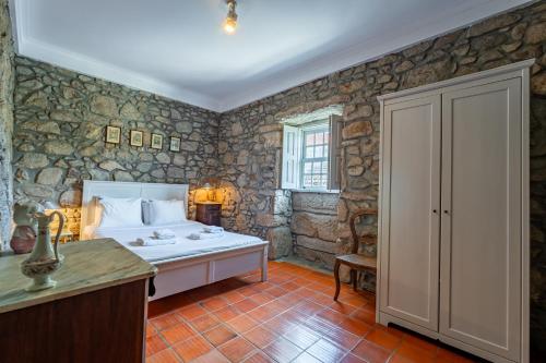 ein Schlafzimmer mit einem Bett in einem Zimmer mit Steinwänden in der Unterkunft Casa das Pintoras Garden and Pool in Vila Praia de Âncora