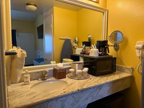 a bathroom counter with a sink and a mirror at Monterey Bay Lodge in Monterey
