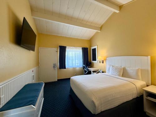 a hotel room with a large bed and a television at Monterey Bay Lodge in Monterey