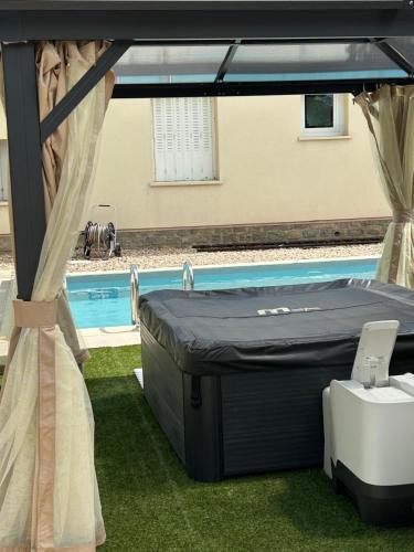 a bed in a tent next to a swimming pool at Jolie Villa indépendante climatisée 3 chambres tout confort 6 couchages, piscine chauffée 4 X 8 disponible selon météo de Mai à fin Septembre, Jacuzzi 4 places, boulodrome éclairé, ping-pong, wifi, proche commerces Animaux domestiques sur demande in Bretenoux