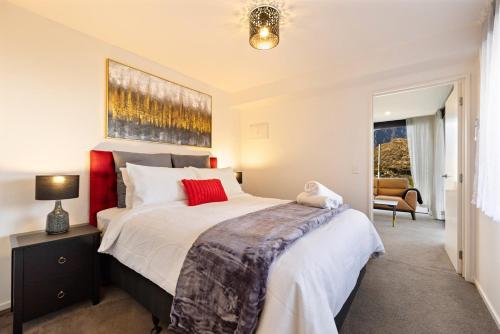 Un dormitorio con una cama grande y una silla. en Lakevista Haven -- Spa Pool - Hot Tub with Views, en Queenstown