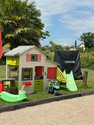 a toy house with a play set on the grass at Jolie Villa indépendante climatisée 3 chambres tout confort 6 couchages, piscine chauffée 4 X 8 disponible selon météo de Mai à fin Septembre, Jacuzzi 4 places, boulodrome éclairé, ping-pong, wifi, proche commerces Animaux domestiques sur demande in Bretenoux