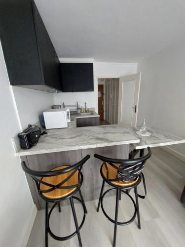 une cuisine avec deux chaises assises à un comptoir dans l'établissement Studio contemporain vue côté mer, à La Baule