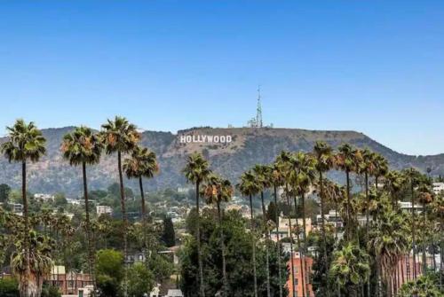a hollywood sign on top of a mountain with palm trees at Modern Escape in Hollywood with Rooftop & City Views in Los Angeles