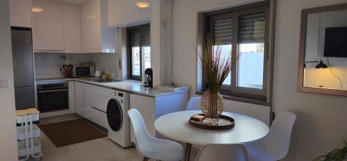 a kitchen with a white table and chairs and a table with a plant at Casa dos Sinos 2Bedroom Beach Apartment with Terrace in Albufeira