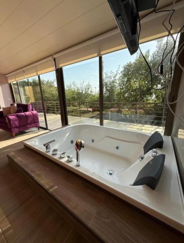 a large bath tub in a room with a large window at Amaruna LB in Al Qarşā