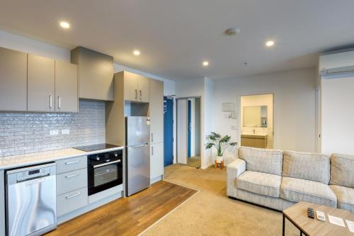 a kitchen and a living room with a couch at Ramada Suites By Wyndham Victoria Street West in Auckland