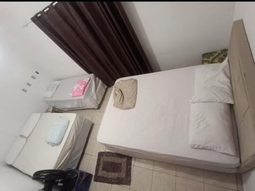 a white bed in a room with two boxes at Pousada lux in Jaraguá do Sul