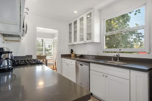 バークレーにあるModern Abode 2BD with Garden and Garageの白いキャビネット、シンク、窓付きのキッチン