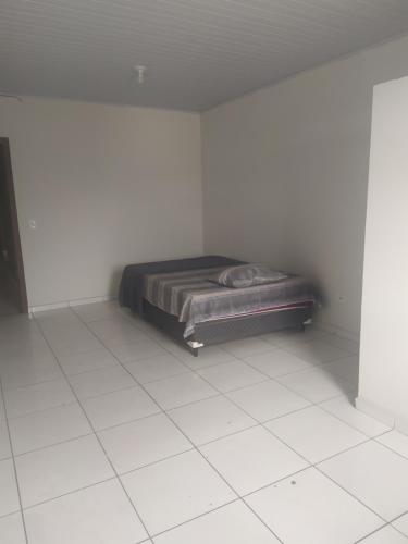 a bedroom with a bed in a white room at Pousada Martins in Teófilo Otoni