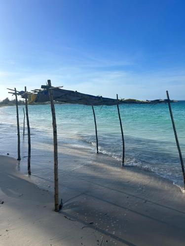 a wooden structure on a beach near the water at Villas Manoel in Lumbo
