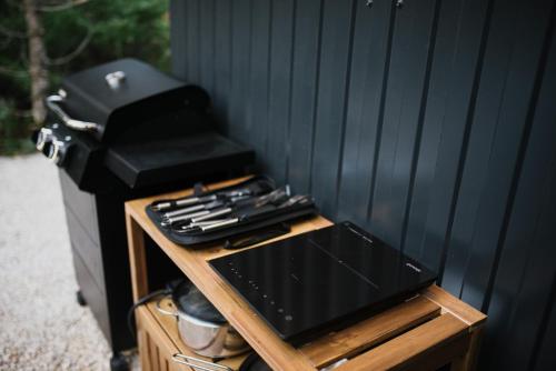 a gas grill sitting on a wooden stand next to a wall at Pinelle Blidinje A-Frame House in Risovac