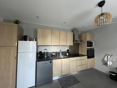 La cuisine est équipée d'un réfrigérateur blanc et de placards en bois. dans l'établissement Le petit Chalet, à La Ferté-Saint-Aubin