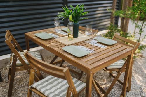 a wooden table with chairs and wine glasses at Pinelle Blidinje A-Frame House in Risovac