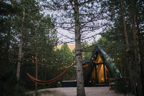 a tent in the woods with a hammock at Pinelle Blidinje A-Frame House in Risovac