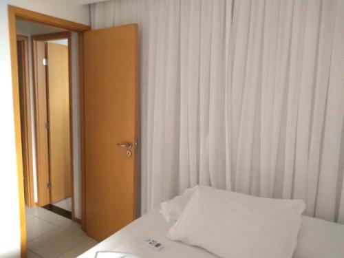 a bedroom with a bed with a white pillow and an open door at Flat Rosarinho Essence in Recife