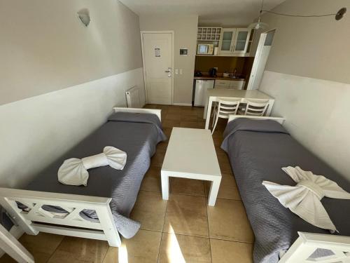 Una pequeña habitación con dos camas y una mesa. en Brisa Marina Apart Hotel, en Pinamar