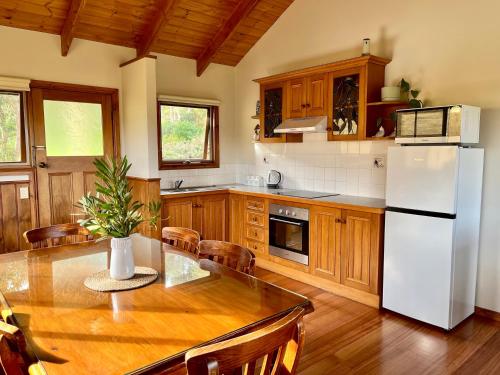a kitchen with a table and a white refrigerator at Daysy Hill Country Cottages in Port Campbell