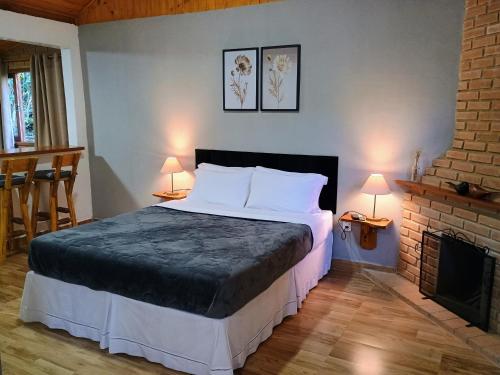a bedroom with a large bed and a fireplace at Chalé Recanto in Visconde De Maua