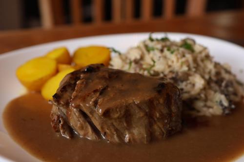 a plate of food with meat and potatoes and gravy at Hotel Recanto do Ouro in Ouro Preto