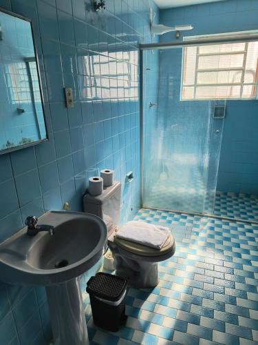 a blue bathroom with a toilet and a sink at Pousada LA VIVIAN in Serra Negra