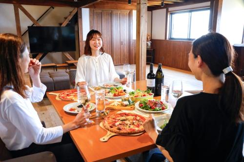 a group of people sitting around a table eating pizza at Iso Ocean Breeze Villa in Kyotango