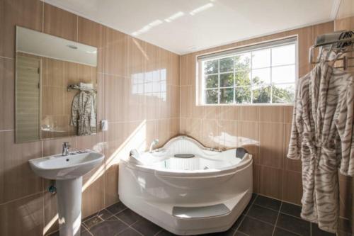 a bathroom with a tub and a sink and a mirror at Jubilee Chalet in Seogwipo