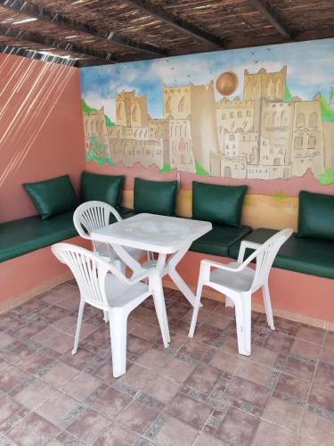 a table and chairs in front of a wall with a mural at Dar Aourir in Aourir