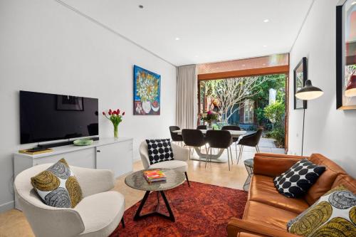 a living room with a couch and chairs and a tv at Stylish Fully Renovated Luxe 3BR, 2BA Balmain Terrace near Parks, Ferry, Cafes & Pubs in Sydney