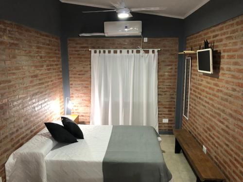 een slaapkamer met een wit bed en een bakstenen muur bij Quinta Mi Quincho in San Pedro