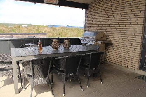 a table and chairs on a patio with a stove at Luxurious 8-Person House With A Spacious Outdoor Spa - 1003 in Ringkøbing