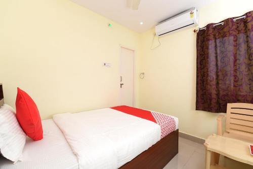 a bedroom with a bed with red pillows and a window at Hotel O Andhra Pradesh Hotels Association in Vijayawada